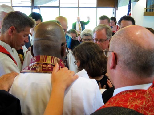Kelli in the midst of the clergy laying hands.