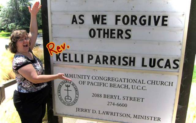 Rev. Kelli mugging at the marquee at church with her name on with "rev." painted in after the fact